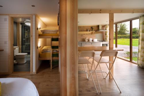 a room with a bed and a kitchen with a table and chairs at Orchard Glamping in Catterall
