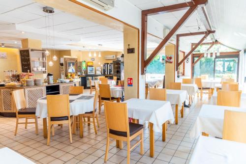 グッサンヴィルにあるHôtel Bagatelle Paris Nord Roissy - ex Inter-Hotelの白いテーブルと椅子、カウンター付きのレストラン