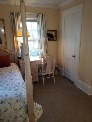 a bedroom with a bed and a desk and a window at English Cottage in Greensboro