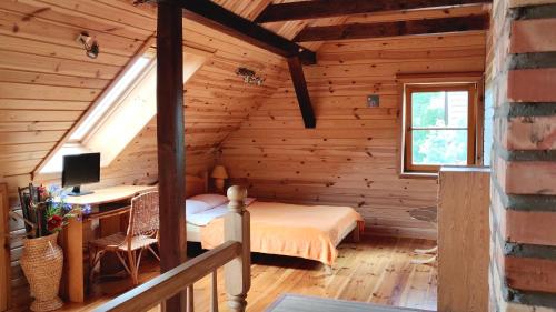 a bedroom in a log cabin with a bed and a desk at Domek nieopodal rzeki Bug in Klepaczew