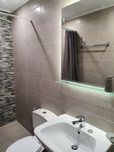 a bathroom with a toilet and a sink and a mirror at Eleana's apartments in Gouvia