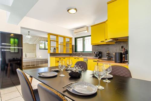 a kitchen with yellow cabinets and a table with wine glasses at Venizelos Studios in Plataniás