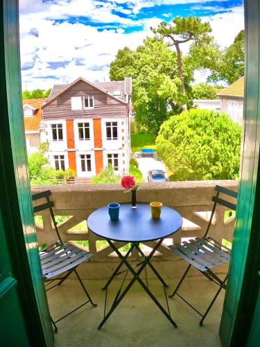 d'une table et de deux chaises sur un balcon avec une fenêtre. dans l'établissement La Jeanne Marcelle T2 50m plage, à Royan