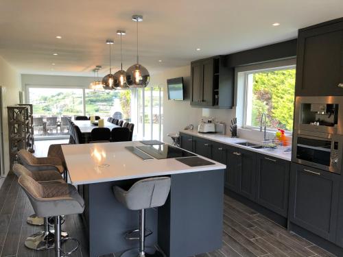 a kitchen with black cabinets and a kitchen island with bar stools at Marina views, Kinsale, Hosted by Exquisite holiday homes, sleeps 20 in Kinsale