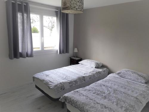 2 bedden in een slaapkamer met een raam bij Villa Louizanne in Saint-Georges-de-Didonne