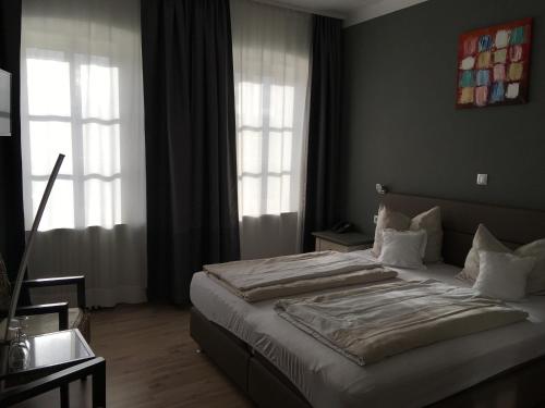 ein Schlafzimmer mit einem großen Bett und zwei Fenstern in der Unterkunft Landhotel Steffen in Lieser