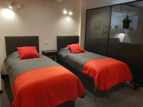 two beds with red pillows in a room at APARTAMENTY VINCI in Krasnystaw