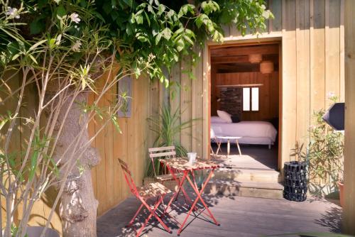 une terrasse couverte d'une maison avec un lit et une table dans l'établissement Centre Cap-ferret, les chambres du phare, bassin, à Cap-Ferret