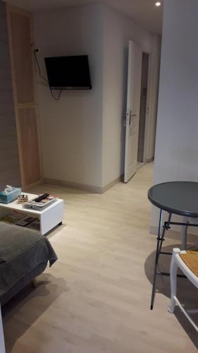 a living room with a table and a tv on the wall at Chez Madgi et Jean-Mi in Froncles