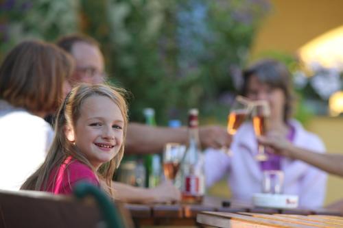 a little girl sitting at a table with a group of people at Ferienhof Uhudler-Arkaden in Stegersbach