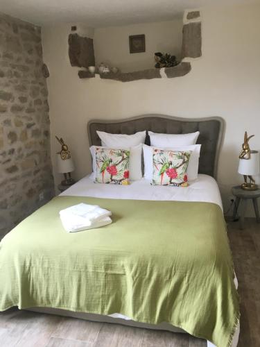 a bedroom with a bed with a green comforter and pillows at La Charmeraie in Montpeyroux