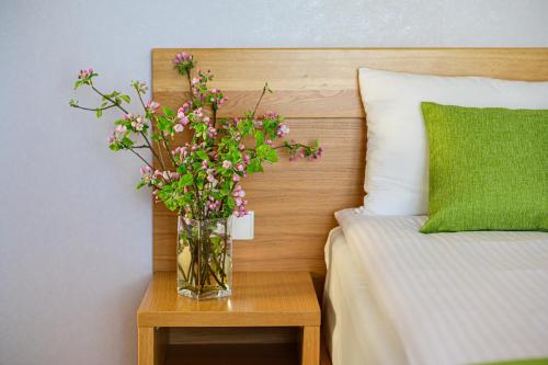 a vase of flowers on a table next to a bed at Hotel Bachledówka in Zakopane