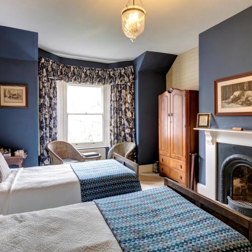 a bedroom with two beds and a fireplace at Victoria House in Church Stretton