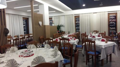 een eetkamer met tafels en stoelen met witte tafelkleden bij Albergo RISTORANTE SOTTOCASTELLO in Cassacco
