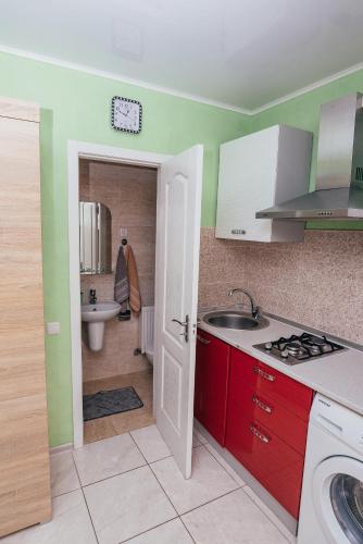 a kitchen with red cabinets and a sink and a bathroom at Guest house VadLen in Odesa