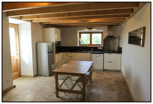 a kitchen with a wooden table and a refrigerator at Gîte du Mas Saint-Victor in Bonnieux