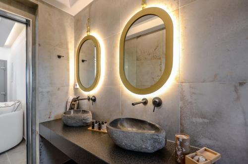a bathroom with two sinks and two mirrors at Naxos Pantheon Luxury Apartments in Agkidia