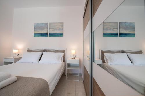 two beds in a small room with two lamps at Bounatsa Studios & Apartments in Nydri
