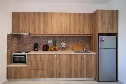 a kitchen with wooden cabinets and a refrigerator at Bounatsa Studios & Apartments in Nydri