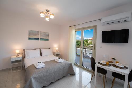 a bedroom with a bed with a television and a balcony at Bounatsa Studios & Apartments in Nydri