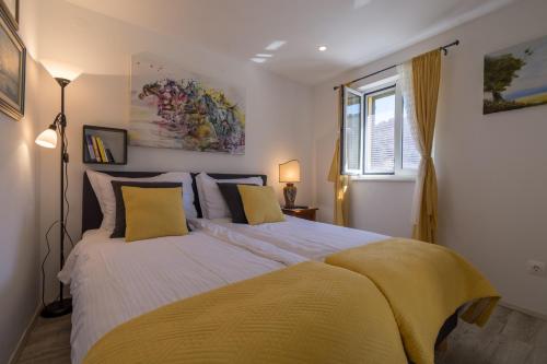 a bedroom with a large bed with yellow pillows at Rokovača in Skradin