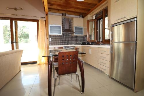 a kitchen with a table and a stainless steel refrigerator at Theonymfi Luxury Villas in Doukádes