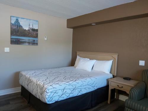 a hotel room with a bed and a chair at Arnprior Motor Inn in Arnprior