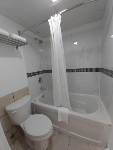 a white bathroom with a toilet and a bath tub at Arnprior Motor Inn in Arnprior