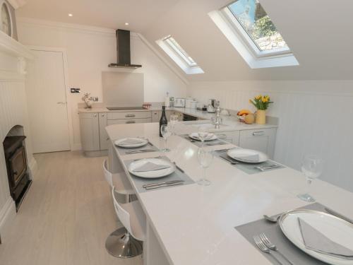 una cocina blanca con una mesa con platos y copas de vino en 1 The Old Coach House, en Dartmouth