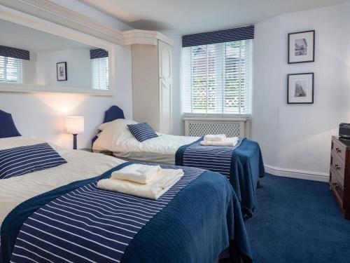 Un dormitorio con dos camas y dos ventanas. en 1 The Old Coach House, en Dartmouth