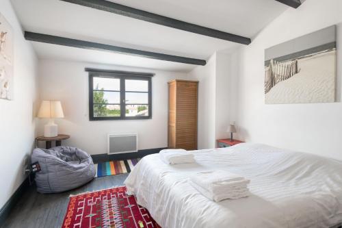 1 dormitorio con cama blanca y alfombra roja en Appartement Bastingage, en Saint-Martin-de-Ré