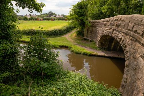 an old stone bridge over a river in a park at Orchard Glamping in Catterall