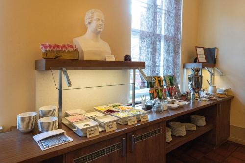 a counter with plates and a bust of a man at Hotel am Großen Waisenhaus in Potsdam