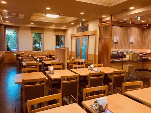 an empty restaurant with wooden tables and chairs at Hotel Route-Inn Hon Hachinohe Ekimae in Hachinohe