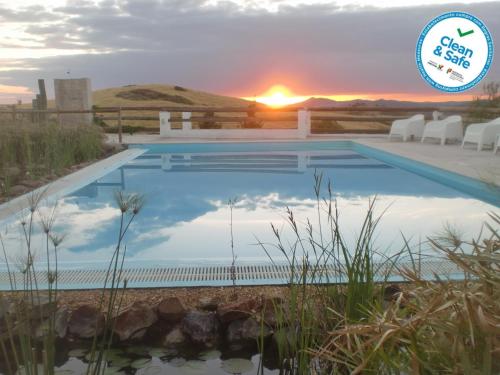 a swimming pool with the sunset in the background at Horta da Quinta in Mértola