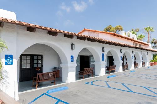 a white building with benches in a parking lot at Holiday Inn Express San Clemente N – Beach Area by IHG in San Clemente