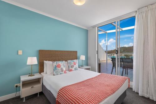 a bedroom with a bed and a balcony at Ettalong Beach Luxury Apartments in Ettalong Beach