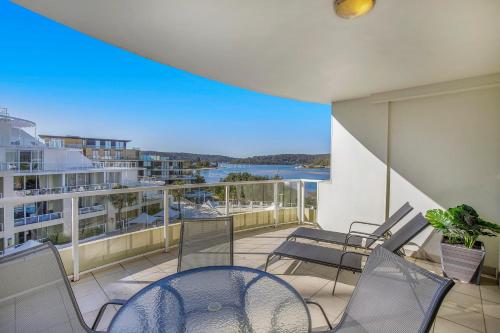 a balcony with chairs and a table on a building at Ettalong Beach Luxury Apartments in Ettalong Beach