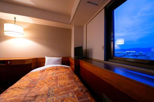 Dormitorio con ventana, cama y TV en Hotel New Green en Nagaoka