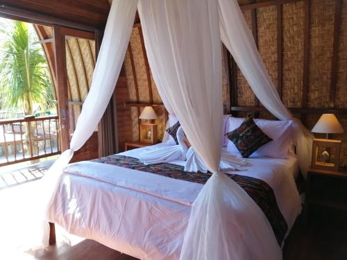a bedroom with a bed with a canopy at Lumbung Bukit Resort Uluwatu in Uluwatu