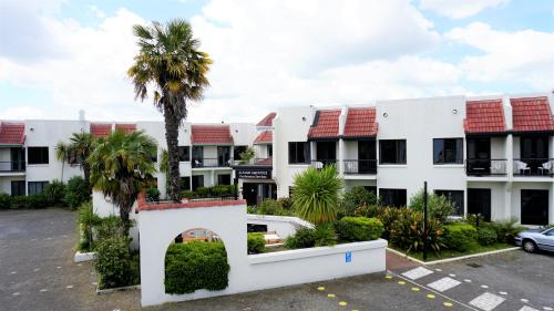 an apartment building with palm trees in a parking lot at Alcamo Motel in Hamilton
