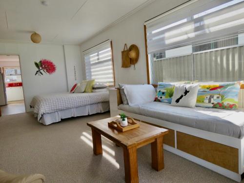 a room with a couch and a bed and a table at Pohutukawa Bach in Whangarei