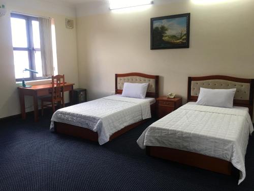 a bedroom with two beds and a desk and a window at Thien Anh Hotel in Hai Phong