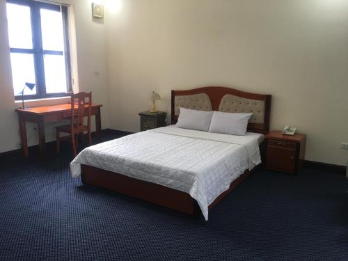 a bedroom with a bed and a desk and a window at Thien Anh Hotel in Hai Phong