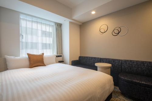 a hotel room with a bed and a couch at Hotel Vista Tokyo Tsukiji in Tokyo