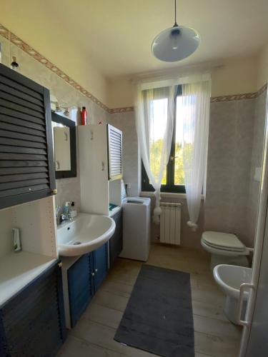 La salle de bains est pourvue d'un lavabo, de toilettes et d'une fenêtre. dans l'établissement Appartamento Nel verde del Parco della Rocca, à Manerba del Garda