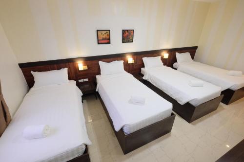 three beds in a room with white sheets at Paraiso Verde Hotel in Koronadal