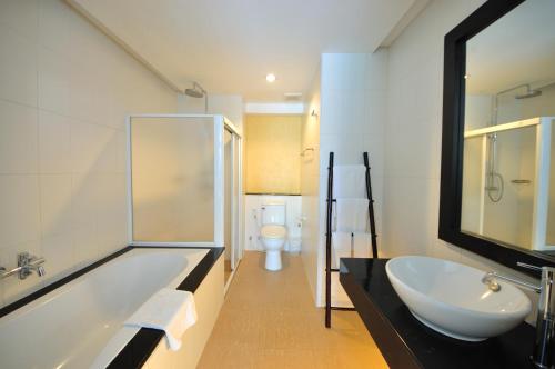 a bathroom with a tub and a sink and a toilet at Palmyra Patong Resort Phuket - SHA Extra Plus in Patong Beach