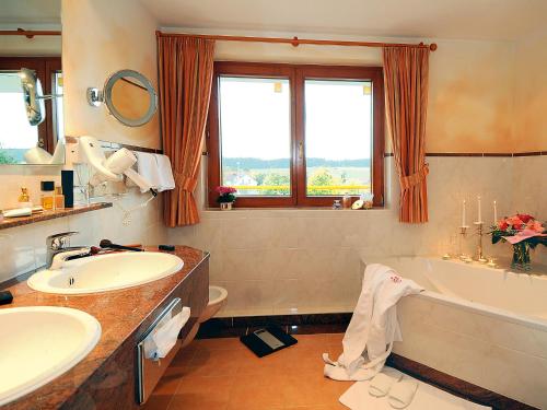 ein Badezimmer mit einer Badewanne, einem Waschbecken und einer Badewanne in der Unterkunft Schwarzwaldhotel Oberwiesenhof in Seewald