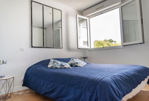 a bedroom with a blue bed with two windows at Spacieux T2 remis à neuf, à 3 min des plages, terrasse in Anglet